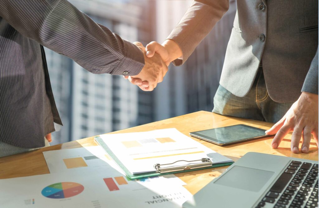 aperto de mão entre dois homens de negócios com relatórios acima da mesa - como ter uma equipe de vendas de alta performance