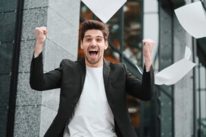 Businessman throwing papers documents into air and celebrates success on office building background. Freedom, successful completion of project concept.