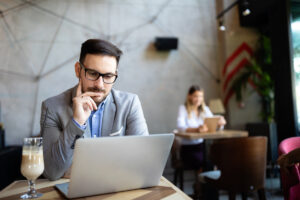 Happy confident businessman working, using laptop in office