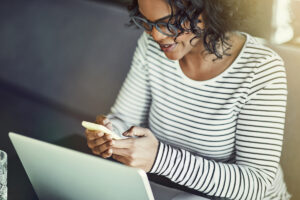 Young African woman using a laptop and reading text messages