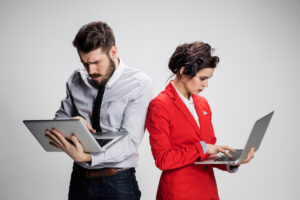 The young businessman and businesswoman with laptops  communicating on gray background